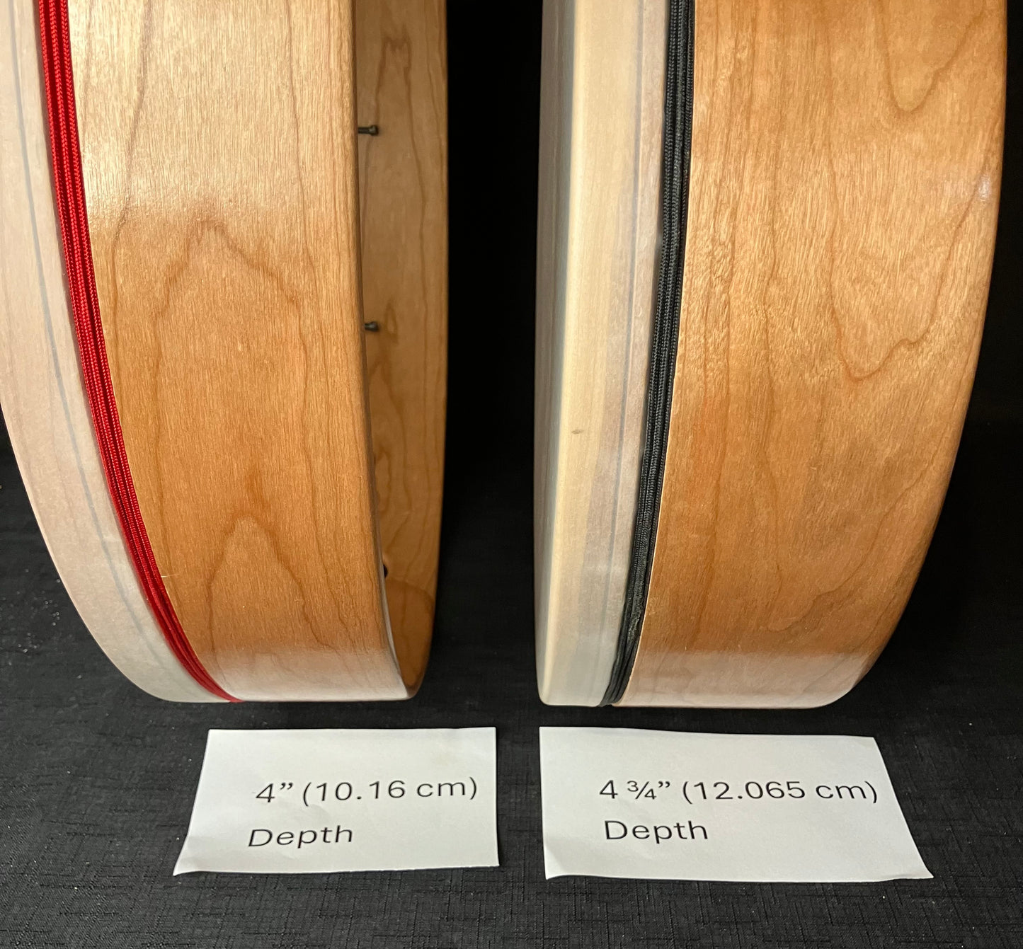 Two hand drums lying flat showing their depth, one marked as 4 inches and the other as 4 3/4 inches.