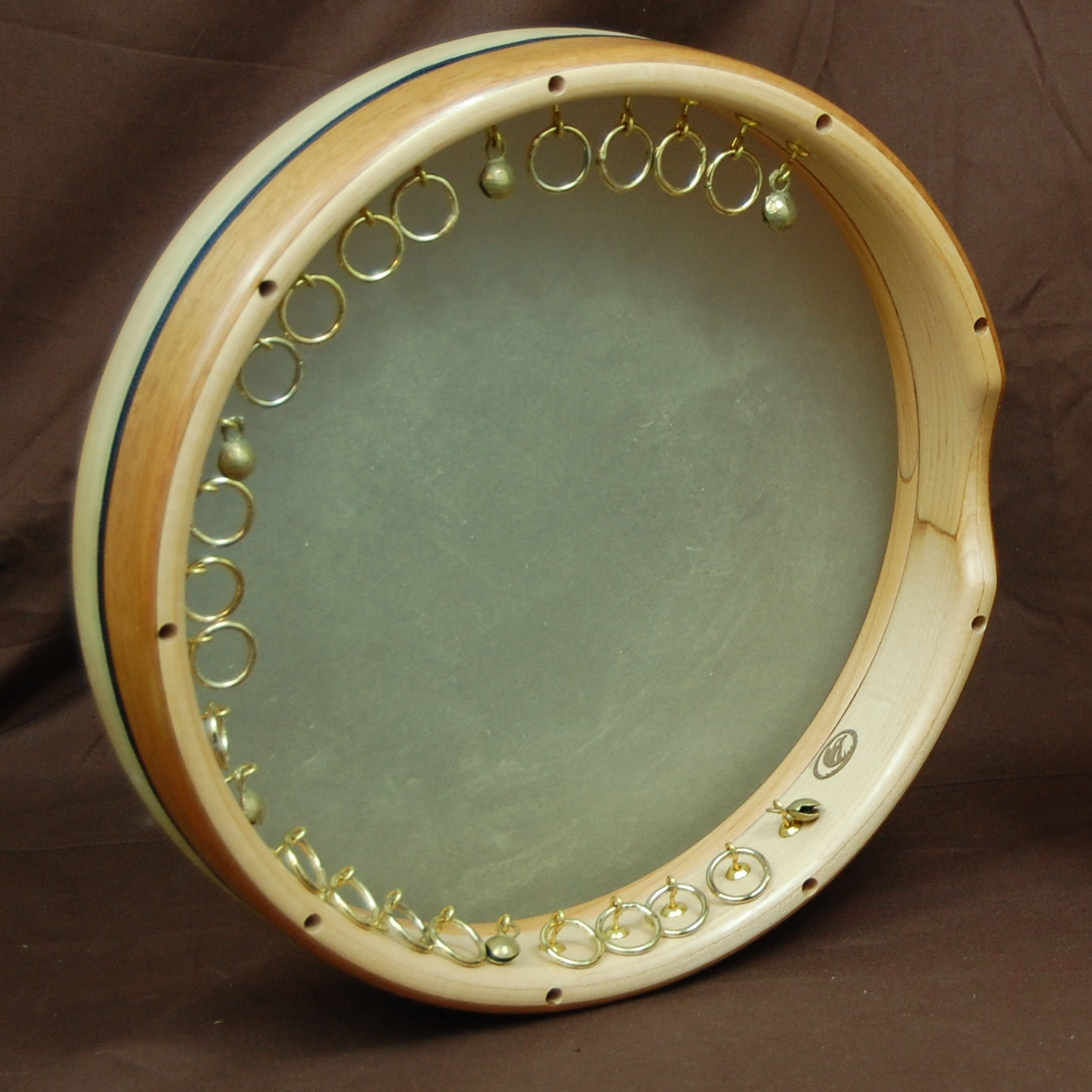 A classic ghaval shell, with a turned maple frame and decorative exotic wood outer flitch, featuring brass rings mounted on small hooks.